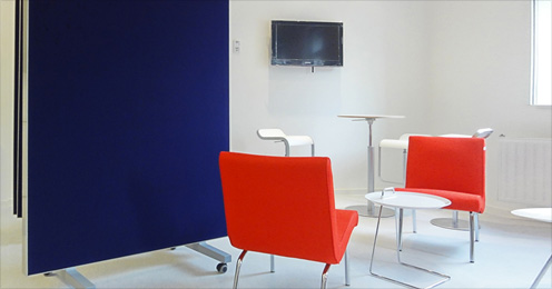 Ein Besprechungsraum mit roten Stühlen und einer blauen schallreflekierenden Schiebewand